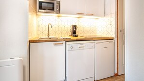 A compact kitchen with white cabinetry, a microwave, a coffee maker, and two dishwashers. - Joubarbes - Station à pied (Chamrousse)