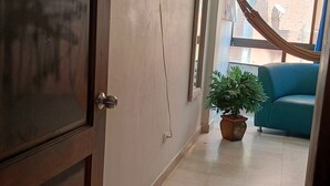 A hallway with a television mounted on the wall, a potted plant, and a blue sofa.
