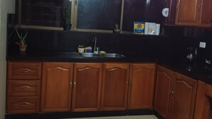 A kitchen with wooden cabinets, a black countertop, a window, and a sink.