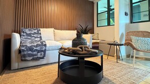 Uma sala de estar moderna com um sofá branco, uma mesa de centro redonda e um ventilador de teto.