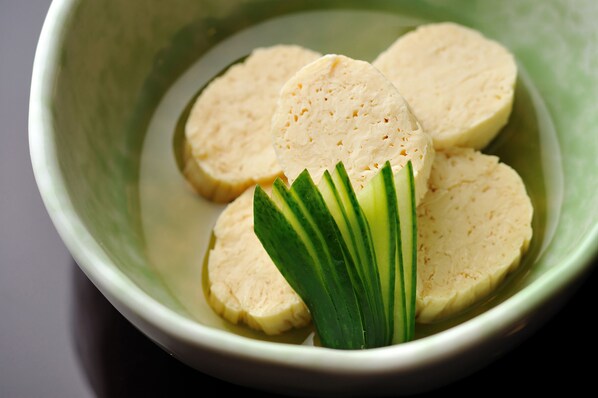 Un bol contenant des tranches de tofu et des lanières de légumes verts.