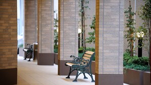 A corridor with benches, brick walls, and greenery. - Hotel Hayashiya Ishinomaki (Isinomaki)
