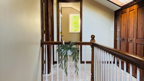 Una escalera con barandilla de madera, un tragaluz y vista a otra habitación.