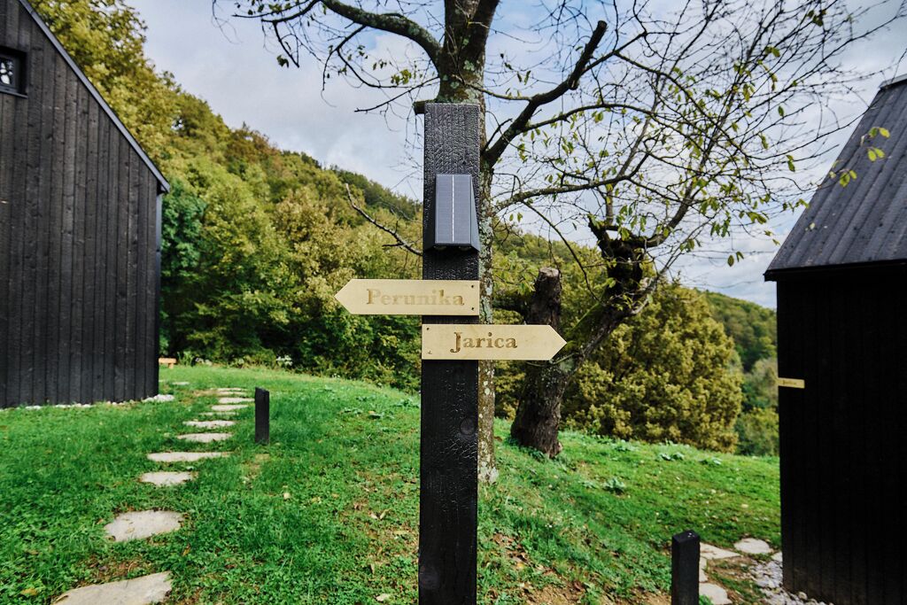 Un panneau indicateur en bois, indiquant les directions vers Pernika et Jarica, entouré d’une zone herbeuse et d’arbres.