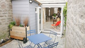 Een kleine binnenplaats met een houten tuinhuisje, een blauwe tafel en stoelen.