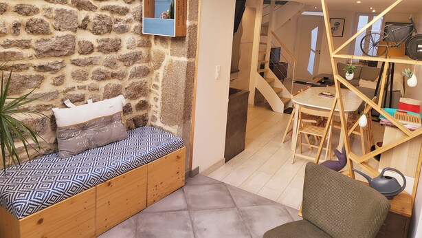 Een gezellige kamer met een stenen muur, een bed met beddengoed met een patroon, een klein tafeltje en een stoel.