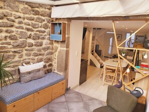 A cozy room with a stone wall, a bed with patterned bedding, a small table, and a chair.