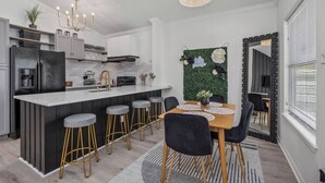 Una cucina moderna con isola centrale, sgabelli da bar e un tavolo da pranzo con sedie.