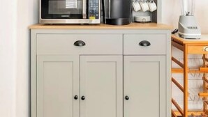 Eine Küche mit einem grauen Schrank, einer Mikrowelle, einer Kaffeemaschine und einem Mixer auf der Arbeitsfläche.
