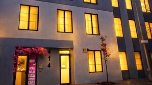 Un hôtel à plusieurs étages, avec des fenêtres illuminées et une enseigne indiquant qu’il est ouvert.