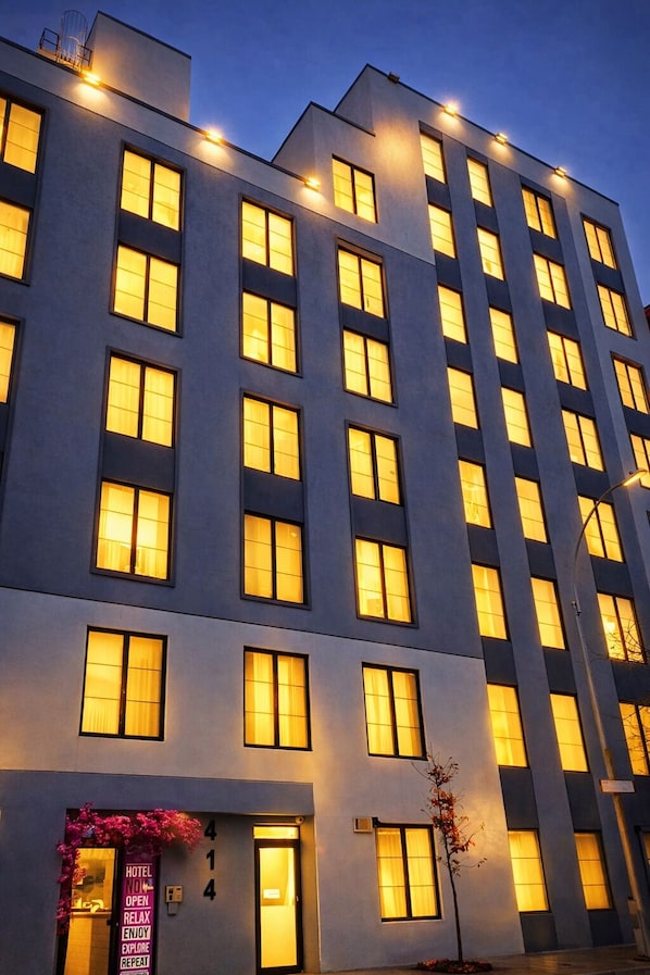A multi-story hotel with illuminated windows and a sign indicating it is open. - ROSE HOTEL BRONX (Bronx)