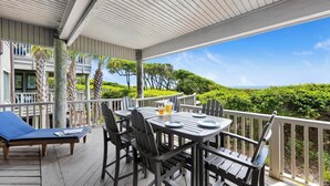 Eine überdachte Terrasse mit Tisch für zwei Personen, Stühlen und einer Liege.