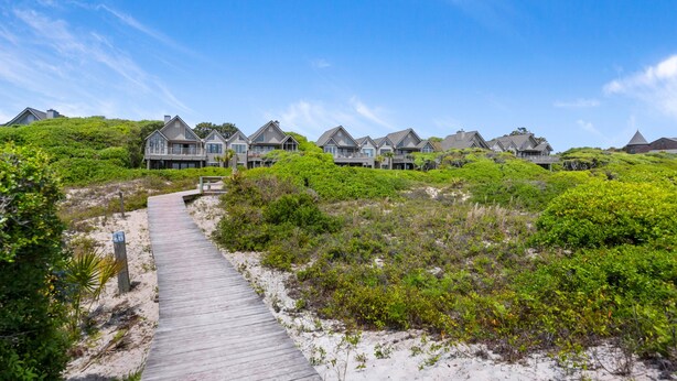 Ein Küstenresort mit mehreren Villen direkt am Strand, verbunden durch eine Holzpromenade.