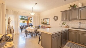 Una cocina moderna con una isla central, armarios oscuros y un comedor con mesa y sillas.
