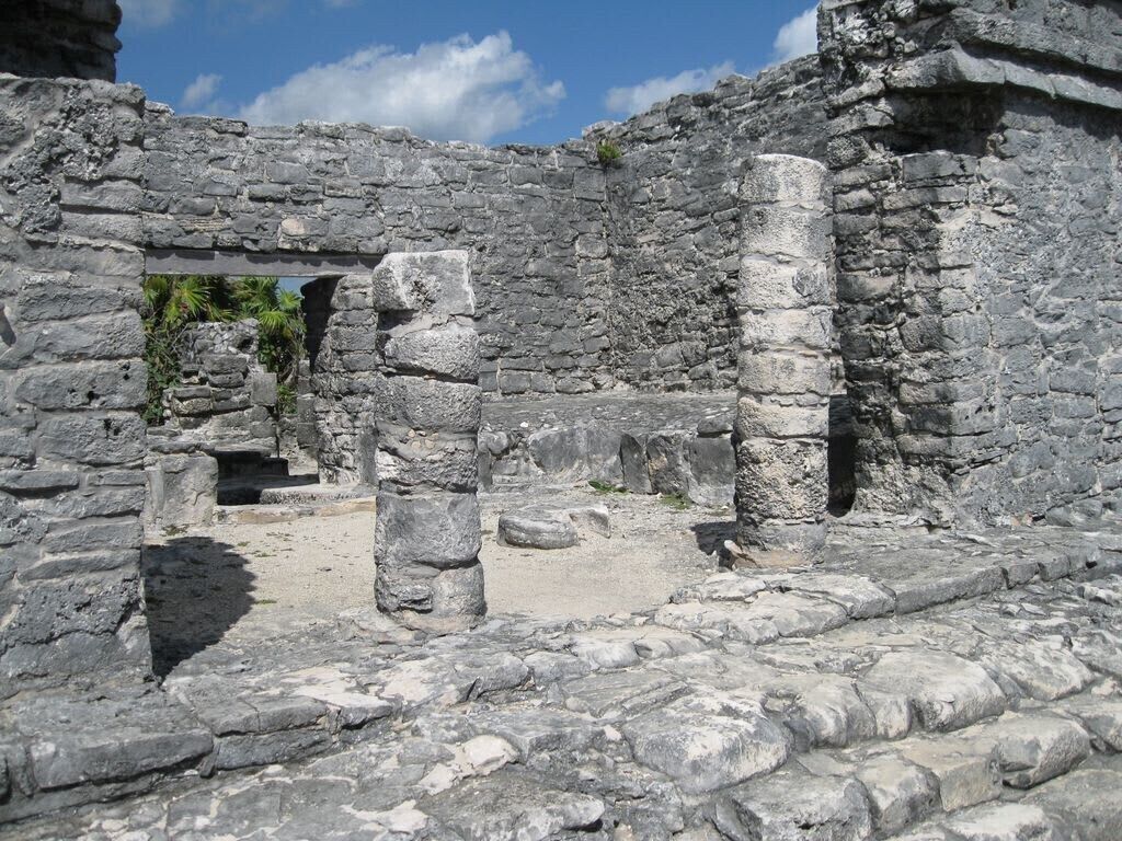 Antiche rovine con mura in pietra e colonne, con un’apertura ad arco e un sentiero.