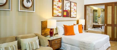 A hotel room with a bed, a sofa, a nightstand, and artwork on the wall.