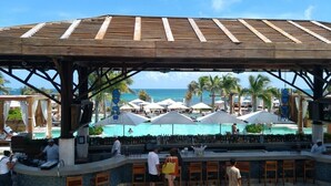 A beachside bar with a view of the ocean and pool area. - 2BD Grand Bliss Vidanta Resort RM (Playa del Carmen)