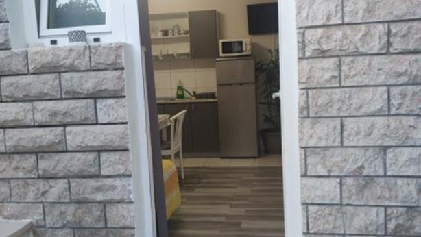 Una cocina con microondas, refrigerador y piso de madera.