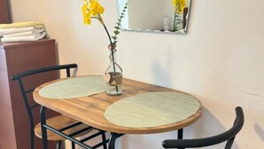 A wooden table with two woven placemats, black chairs, a vase with yellow flowers, and a mirror on the wall. - Apartments Villa Mira Roso - Studio Apartment 3 (Makarska)