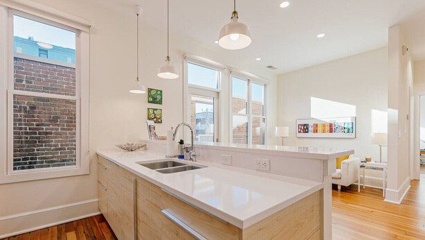 A modern kitchen with a large island, double sink, and pendant lighting. - The Daily Condo 201 at ATB (Asheville)