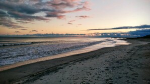 A beach with a pier extending into the water, sandy shore, and a sunset sky. - Cozy studio with AC, WiFi, pool and is just steps from the beach! (Atlantic Beach)