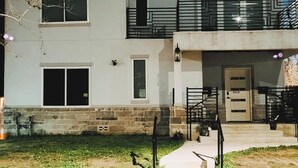A two-story house with a front porch, a visible garage door, and a small front yard. - Urban Oasis Retreat - Unit # 1 & 2 (Houston)