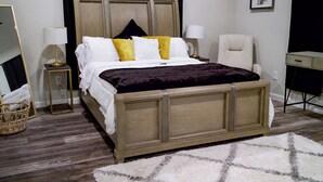 A bedroom with a wooden bed, two bedside tables with lamps, a chair, a desk, and a large mirror. - Urban Oasis Retreat - Unit # 1 & 2 (Houston)