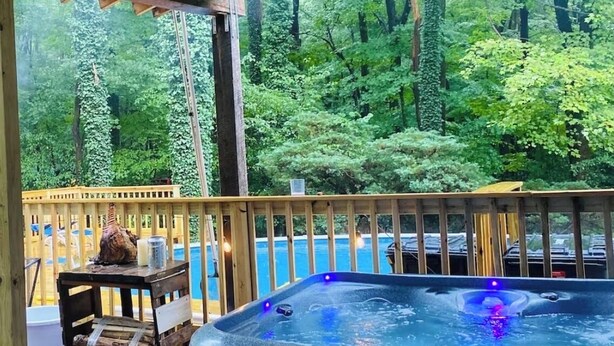 A hot tub on a wooden deck with a view of a forest.