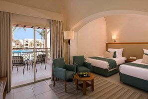 A hotel room with a balcony, two beds, a table with fruit, and a view of buildings. - Magic World Sharm - Club By Jaz (Sharm El Sheikh)