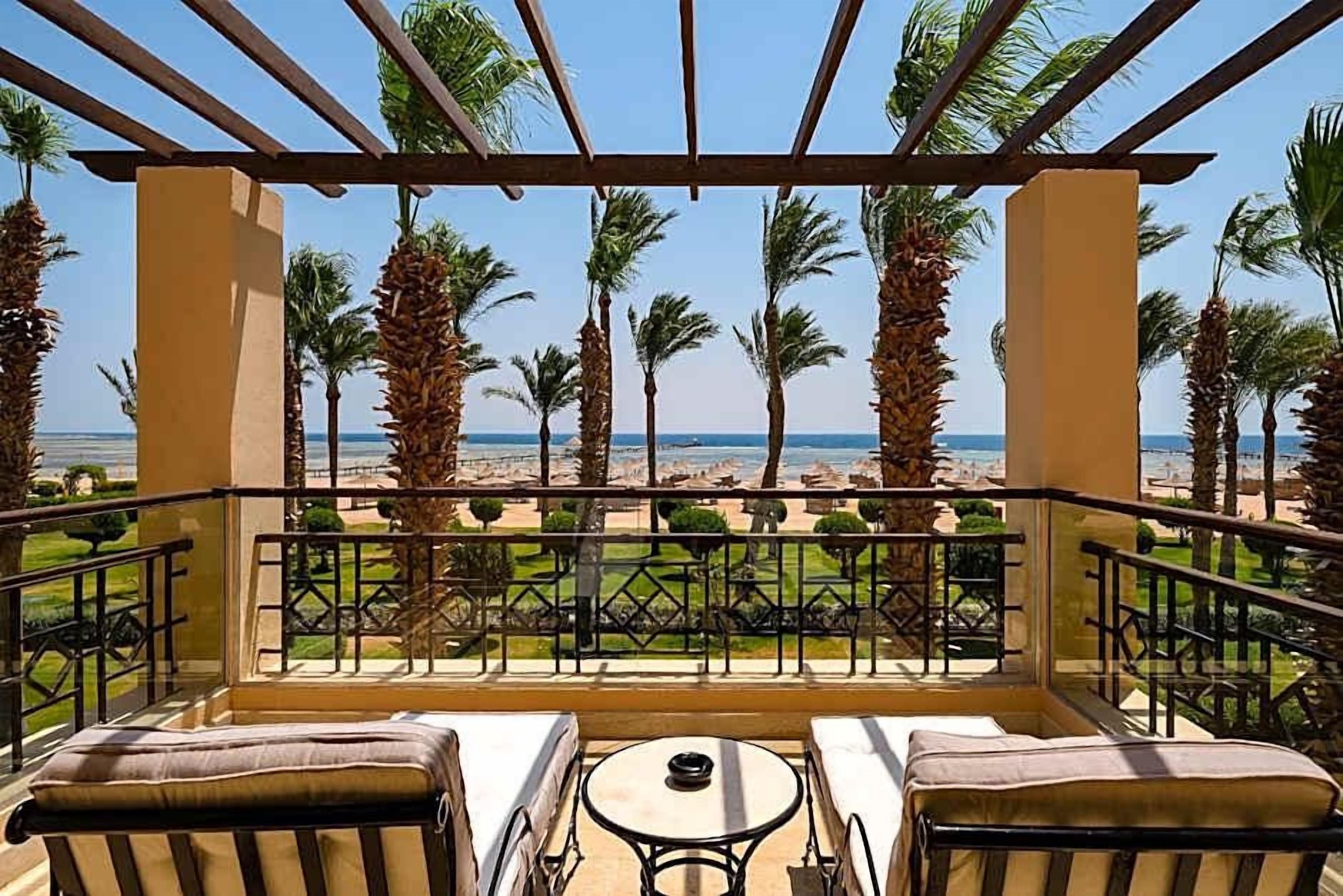 Un balcon avec vue sur la plage, les palmiers et un ciel dégagé.