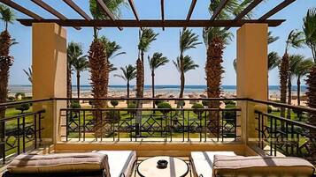 Un balcon avec vue sur la plage, les palmiers et un ciel dégagé.