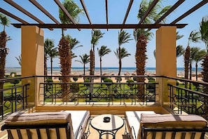 A balcony with a view of the beach, palm trees, and a clear sky. - Magic World Sharm - Club By Jaz (Sharm El Sheikh)