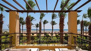 A balcony with a view of the beach, palm trees, and a clear sky. - Magic World Sharm - Club By Jaz (Sharm El Sheikh)