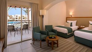 A hotel room with a balcony, two beds, a table with fruit, and a view of buildings. - Magic World Sharm - Club By Jaz (Sharm El Sheikh)