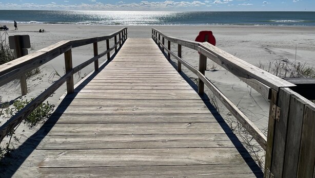A wooden boardwalk leading to a beach with a clear sky and ocean in the background. - Charming 2-bedroom condo in delightful Pawleys Island with AC, WiFi.   (Pawleys Island)