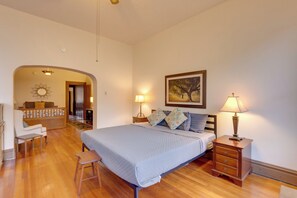 Une chambre à coucher avec un lit, des tables de chevet, une commode, une lampe, un tableau et un plancher en bois.
