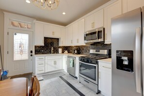 Una cucina moderna con mobili bianchi, elettrodomestici in acciaio inossidabile e un forno a microonde integrato.
