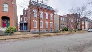 A row of brick townhouses with front porches, a sidewalk, and a street. - STL Apartment: Close to Downtown! (St. Louis)