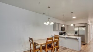 A modern kitchen with a wooden dining table and chairs, stainless steel appliances, and pendant lighting. - 15 Mi to Sundance: Pet-Friendly Condo in Vineyard (Vineyard)