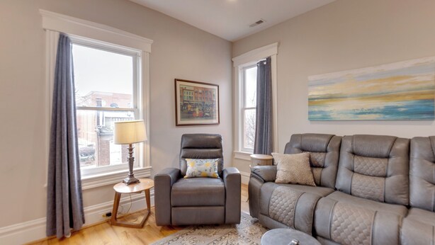Un salon avec un canapé en cuir, un fauteuil inclinable, une petite table avec une lampe et un tableau accroché au mur.