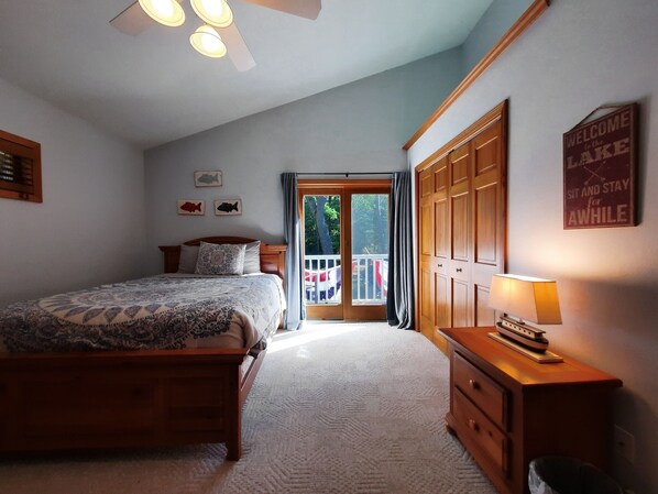 A bedroom with a bed, a dresser, a nightstand, a lamp, and a sign on the wall.