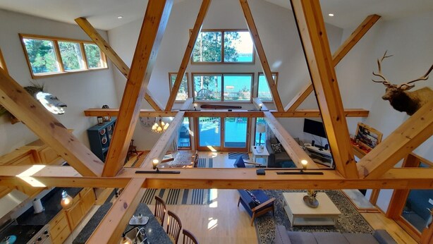 Un loft amplio con techos altos, vigas de madera a la vista, un comedor espacioso y vistas al exterior.