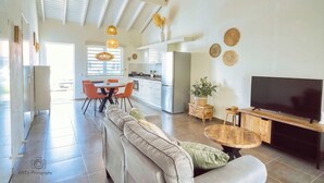 Ein geräumiger Wohnbereich mit Sofa, Esstisch und Fernseher.