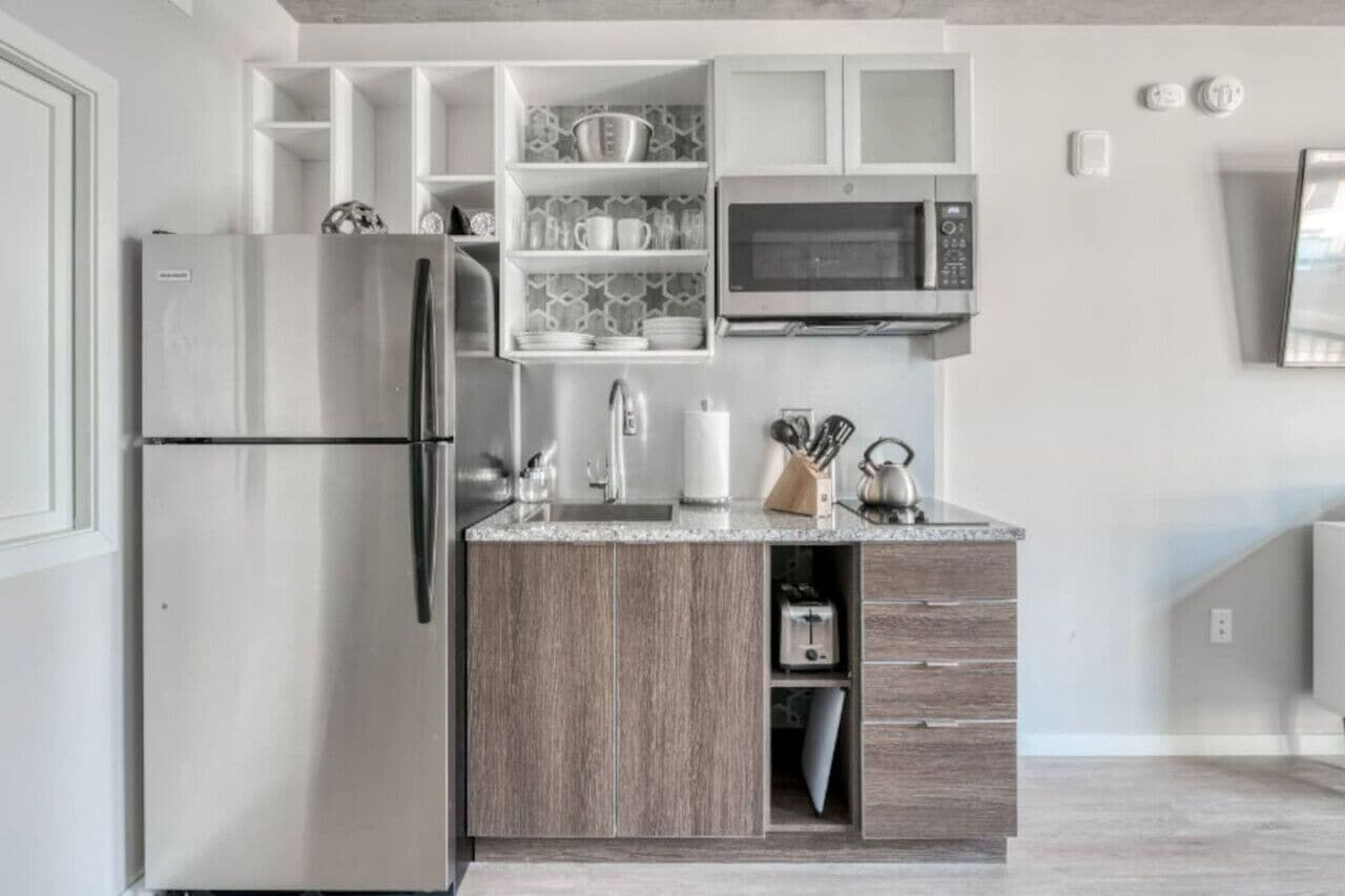 A modern kitchen with a stainless steel refrigerator, a microwave, and wooden cabinetry.