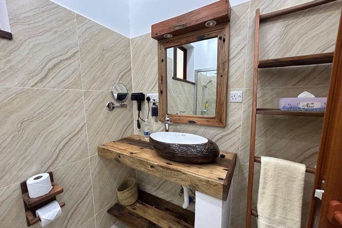 A bathroom with a wooden vanity, a round sink, a mirror, and a towel rack.