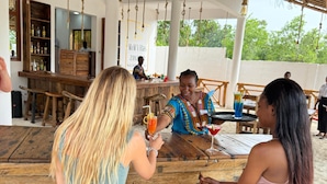 A wooden outdoor seating area with a bar and a sign for 'M&M Villas Zanzibar'. - M&m Villas Zanzibar (Kidoti)