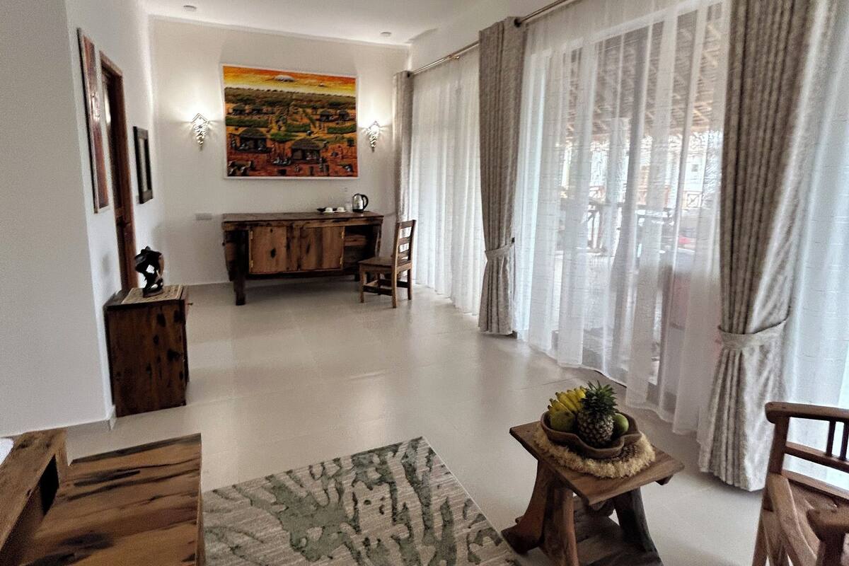A spacious living room with a wooden coffee table, a rug, and a kitchen in the background.