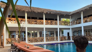 A pool area with lounge chairs and a large decorative vase. - M&m Villas Zanzibar (Kidoti)