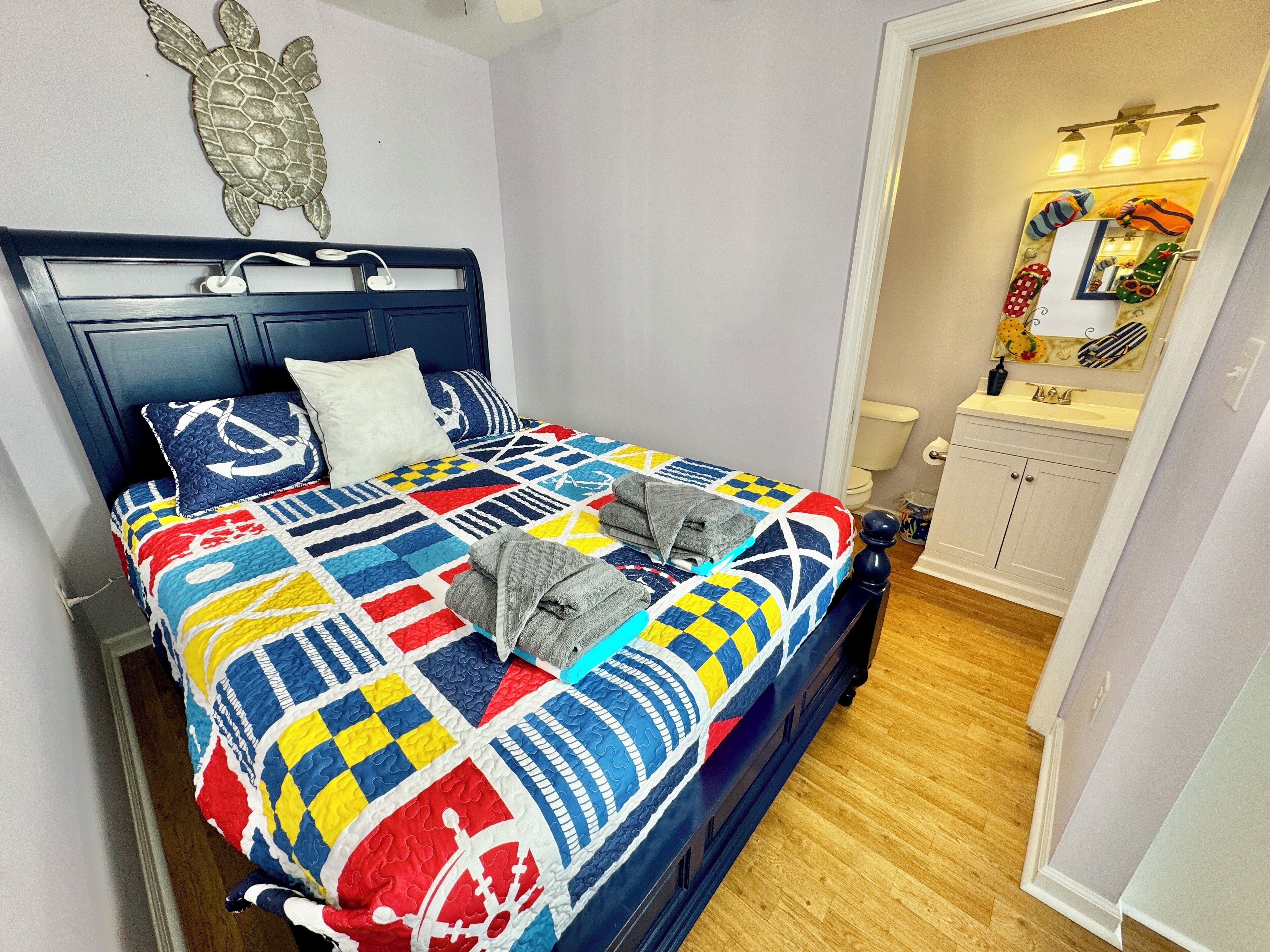 Una cama bien hecha con un colcha colorida, un cabecero y una decoración de pared con una tortuga.