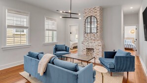 A modern living room with blue sofas, a fireplace, and a large window. - The Philip's Suite, newly renovated 3 Bed/3 EnSuite Bath, 1 Block to King (Charleston)